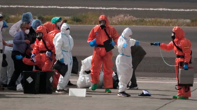 FILE -- Passengers are sprayed with disinfectant by Spanish government officials before...