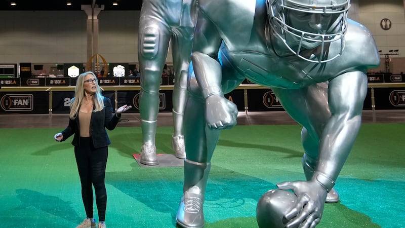 FILE - ESPN anchor Linda Cohn reports next to large images of football players at a fan fest...